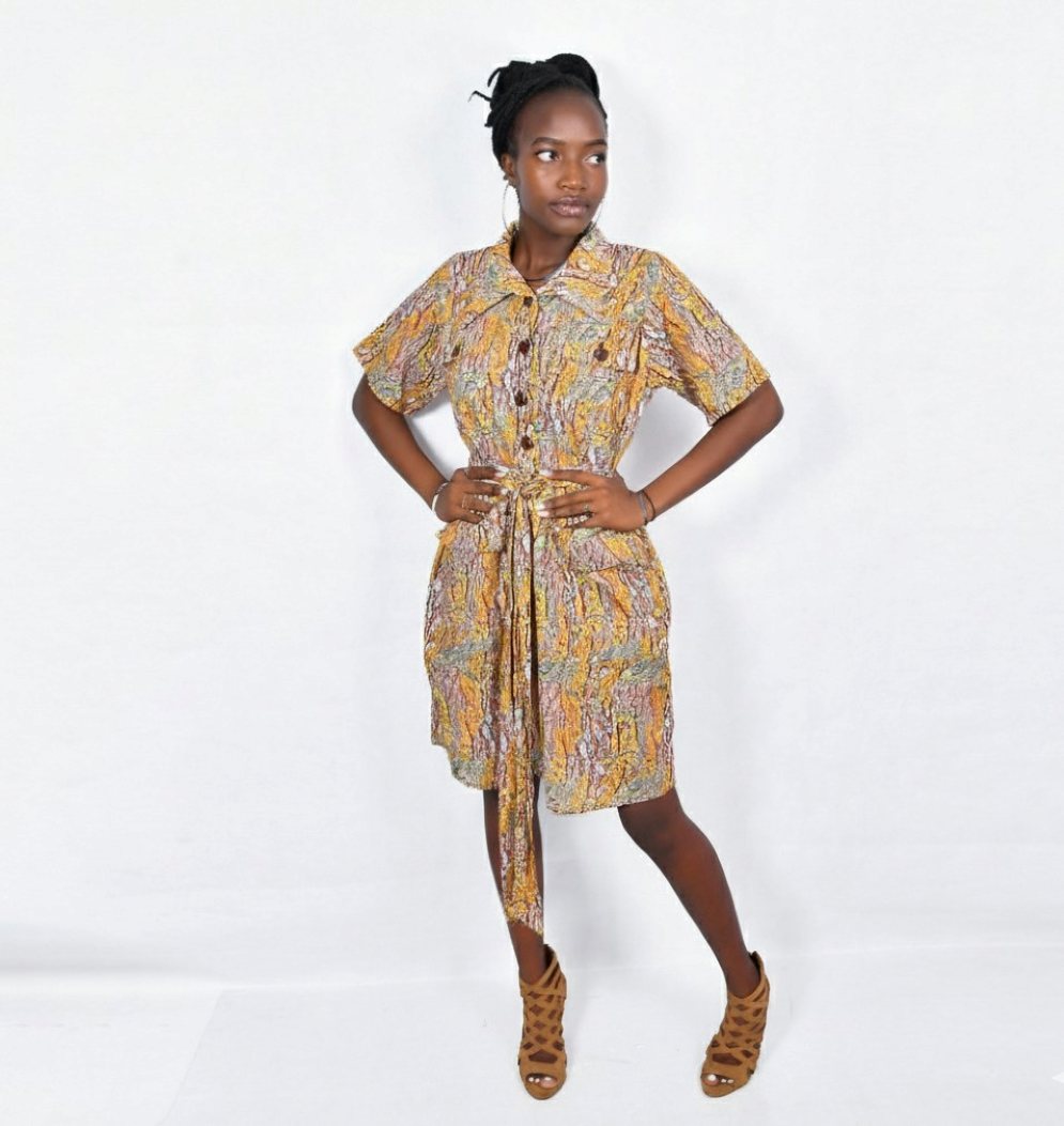 A woman wearing the vibrant, patterned Mara Safari Dress styled open as a lightweight duster jacket over a plain white t-shirt and denim jeans.