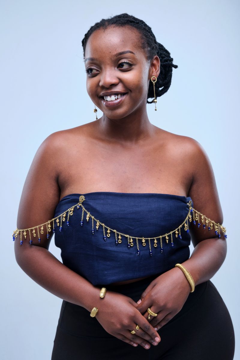 The Mukelewe Body Chain fuses high fashion with wearable sculpture, beautifully draping intricate glass beadwork and warm African brass over your shoulders. This stunning, armor-style masterpiece layers effortlessly over any dress, instantly transforming your look into a high-drama editorial statement.
