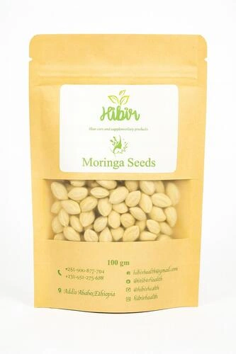 Packaged 100g bag of raw moringa seeds wellness superfood, featuring a clean green and white brand label on a resealable kraft pouch showing peeled miracle tree seed kernels.